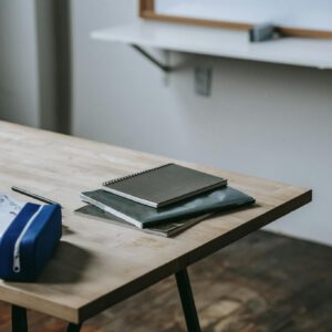 A neatly organized classroom desk with notebooks, papers, and pen case in a modern educational setting.