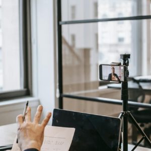 A person conducting an online education session using a laptop and smartphone.