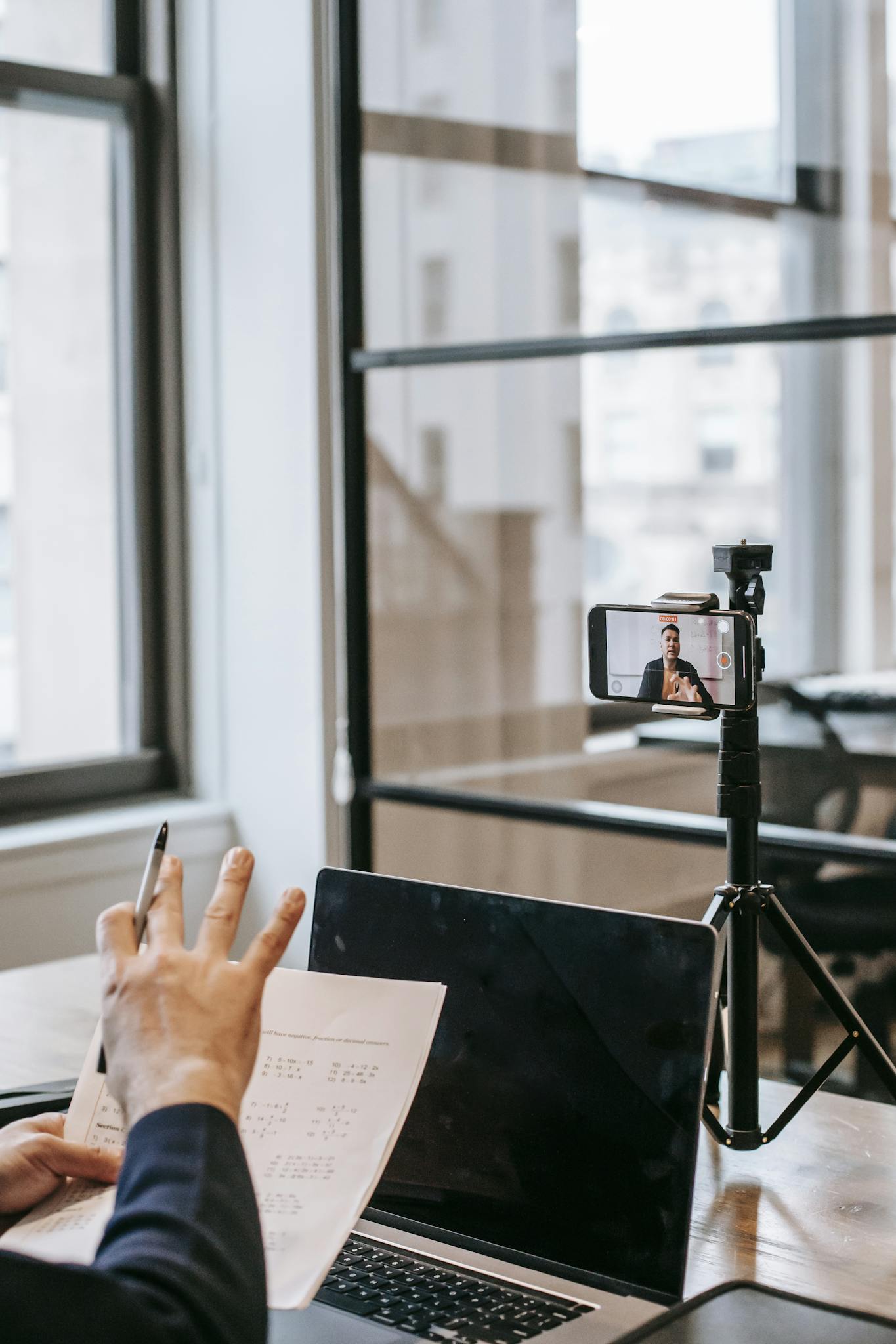 A person conducting an online education session using a laptop and smartphone.