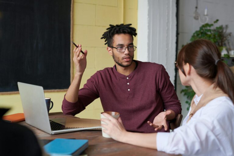 Two colleagues engaged in a collaborative discussion during a team meeting at the office.